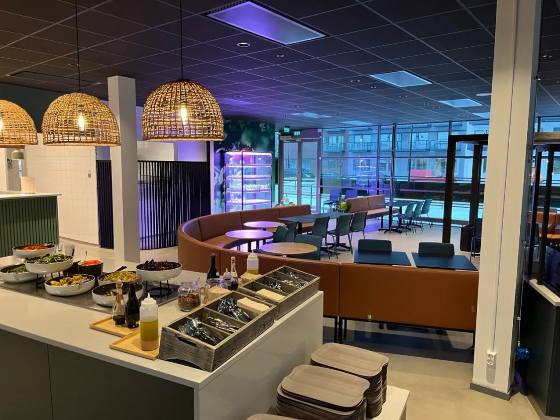 Lunchrestaurang med salladsbuffé och sittgrupper i en ljus lokal